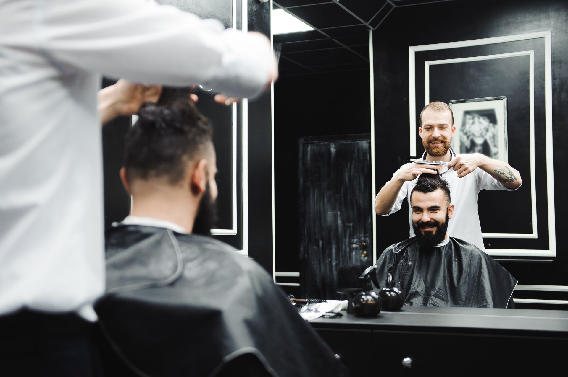 Young handsome barber making haircut of attractive man in barbershop Young handsome barber making haircut of attractive man in barbershop
